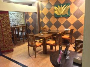 Kuta Sari House في كوتا: مطعم بطاولات وكراسي خشبية وجدار