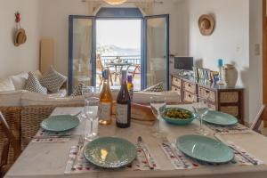 a table with plates and wine bottles and glasses at Almyrida Beach Bungalow Sea Front in Chania