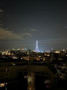 a city at night with a lit up tower in the distance at Montparnasse - Vue Tour Eiffel - Balcon in Paris