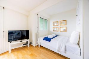 a white bedroom with a bed and a tv at Montparnasse - Vue Tour Eiffel - Balcon in Paris