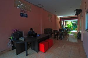 a man sitting at a table with a laptop in a restaurant at Pesona Beach Inn in Kuta