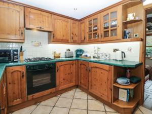 une cuisine avec des placards en bois et des comptoirs verts dans l'établissement Brook Cottage, à Hayfield