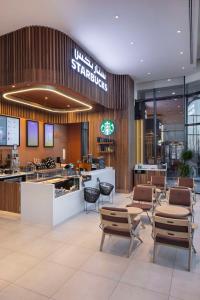 a lobby with tables and chairs in a building at Hampton By Hilton Kuwait Salmiya in Kuwait
