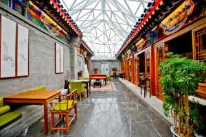 een restaurant met tafels en stoelen en een glazen plafond bij Cours Et Pavillons in Beijing