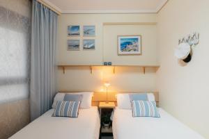 two beds in a small room with a lamp at RESORT BEACH VALENCIA in Valencia +74 photos