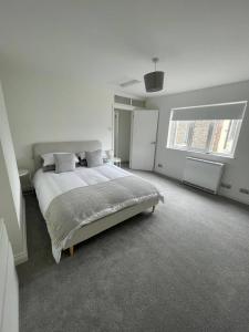 une chambre blanche avec un grand lit et deux fenêtres dans l'établissement Seaside Retreat - Sleeps 5 garden & parking, à Cromer