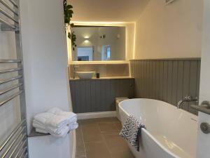 une salle de bain avec une baignoire et un miroir dans l'établissement Seaside Retreat - Sleeps 5 garden & parking, à Cromer