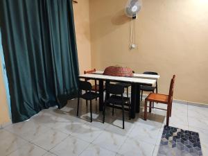 a dining room table with chairs and a green curtain at Qu Homestay in Pasir Puteh