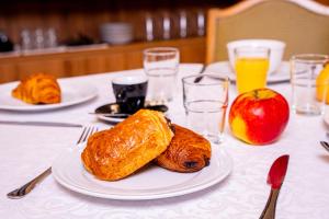 a table topped with plates of pastries and an apple at Breeze Hotel in Calais