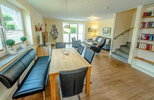 sala de estar con mesa de madera y sillas de cuero en Ferienhaus Niedertor, en Bensersiel