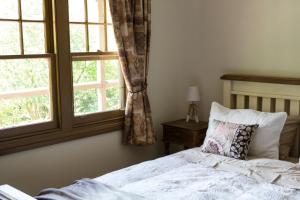 a bedroom with a bed and two windows at Buttercup Hill in Warburton