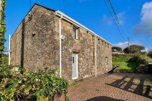 an old stone building with a white door at Finest Retreats - Trennal Barn in Germoe