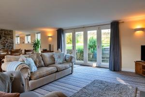 a living room with a couch and sliding glass doors at Finest Retreats - Trennal Barn in Germoe