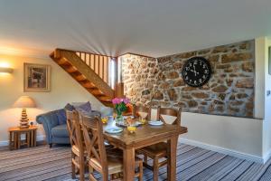 a dining room with a table and a clock on the wall at Finest Retreats - Trennal Barn in Germoe