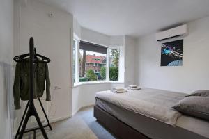 a white bedroom with a bed and a window at The Art Gallery - Mario's Place - By T&S in Eindhoven +6 photos