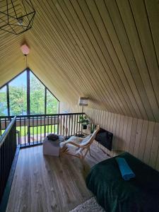 a bedroom with a wooden roof with a bed and a chair at Hytte Na Wyspie -,,Roztoczańskie Morze'' in Kulików