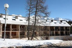 a snow covered building with a tree in front of it at Studio Auron 4 couchages in Saint-Étienne-de-Tinée