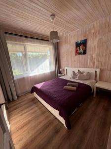 a bedroom with a bed with purple sheets and a window at Sodyba Po klevu in Molėtai