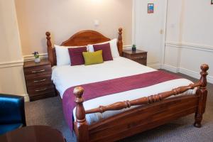 a bedroom with a large wooden bed with pillows at Adelphi Hotel in Liverpool
