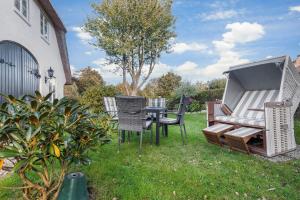 a grill and chairs and a table in a yard at Dohlenhof Das Scheunentor in Keitum
