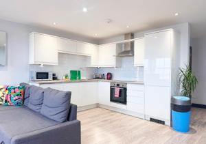 a kitchen with white cabinets and a couch in a living room at The Sunset Apartment - Margate Beach - By Goldex Coastal Breaks in Margate