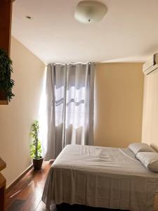 a bedroom with a bed and a window at Apê Letícia I Ar condicionado, wifi e garagem na Zona Sul de BH in Belo Horizonte