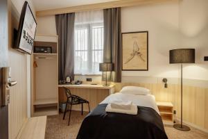 a hotel room with a bed and a desk at Hotel Dworski Galaktyczny Park in Szczecin