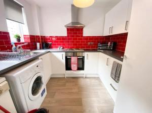 cocina con lavadora y azulejos rojos en Central two bedroom, Free private parking, en Glasgow