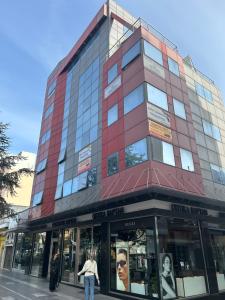 un edificio rojo alto con gente caminando delante de él en VARTAN LUX apt, en Alexandroupoli