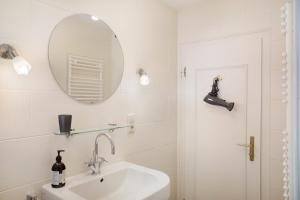 une salle de bain blanche avec un lavabo et un miroir dans l'établissement Alpen Lodge, à Garmisch-Partenkirchen 32 autres photos