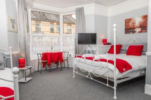 a bedroom with a bed with red pillows and a table at sark guest house in Barnstaple