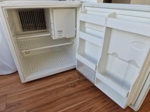 a white refrigerator with its door open on a wooden floor at Private Room Terrace in Kirchheim