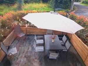 a patio with a table and chairs and an umbrella at Sous la Charpente in La-Roche-en-Ardenne