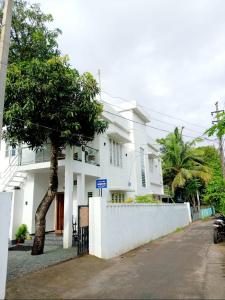 a white house with a tree in front of it at Rohini Homestay & Serviced Villa-Explore Alleppy in Alleppey +11 photos