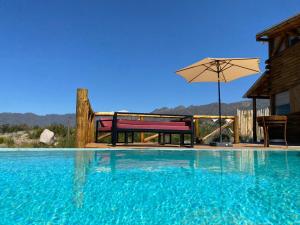 a swimming pool with a bench and an umbrella at Cabaña Vista del Plata in Las Compuertas