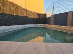 a swimming pool next to a fence and a building at APARTAMENTOS MALPAÍS in Los Barros
