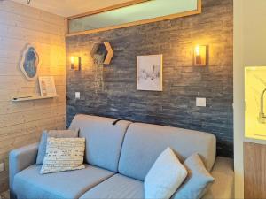La Plagne TarentaiseにあるLe Nuage - 2050 Belle Plagne, F2 Ski aux piedsのレンガの壁の客室で、青いソファが備わります。