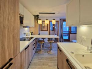 La Plagne TarentaiseにあるLe Nuage - 2050 Belle Plagne, F2 Ski aux piedsの白いカウンターとスツール付きのテーブルのあるキッチン