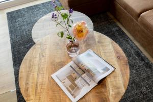 a table with a vase of flowers and a book at Residences Central Winterberg in Winterberg +71 photos