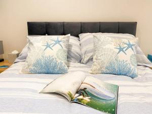 a bed with pillows and an open book on it at Cosy Coastal Getaway in West Wittering