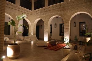a large living room with white furniture and a brick wall at Dar Fatima Elbahbouha in Tozeur