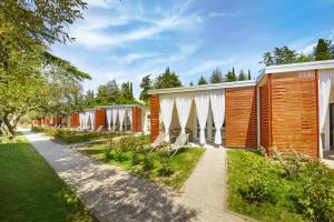 a row of cottages in a garden with a sidewalk at Adria Apartments - Hotel & Resort Adria Ankaran in Ankaran