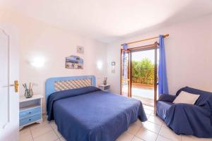 sypialnia z niebieskim łóżkiem i przesuwnymi szklanymi drzwiami w obiekcie Holiday home in Golfo Aranci 30357 w mieście Golfo Aranci