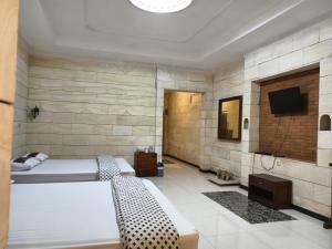a bedroom with two beds and a tv on a wall at Lotus 2 Guest House in Borobudur