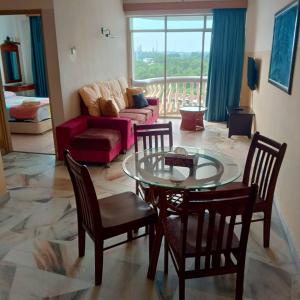 Muslim homestay Glory Beach Resort في بورت ديكسون: غرفة معيشة مع طاولة وكراسي زجاجية