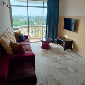 Muslim homestay Glory Beach Resort في بورت ديكسون: غرفة معيشة مع أريكة وتلفزيون