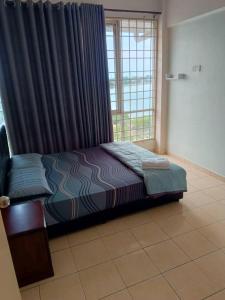 Muslim homestay Glory Beach Resort في بورت ديكسون: غرفة نوم بسرير ونافذة مع ستائر