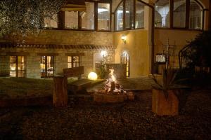kobieta siedząca przy ogniu przed budynkiem w obiekcie Ai Cadelach Hotel Giulia w mieście Revine Lago