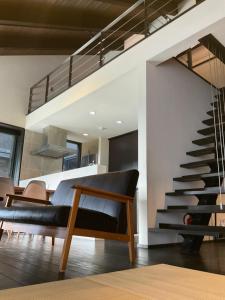 a living room with a staircase and a couch at 奄美大島の宿 in Tatsugo