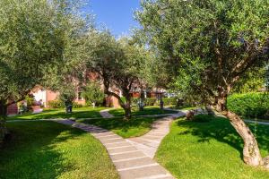 a walkway through a park with trees and grass at Cala Rosa Club Hotel in Stintino
